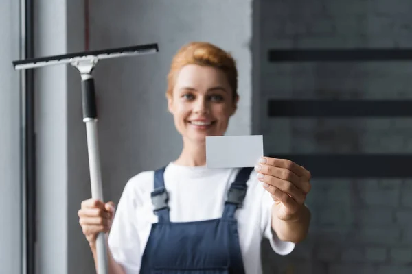 Happy woman with window squeegee holding blank business card — Stock Photo