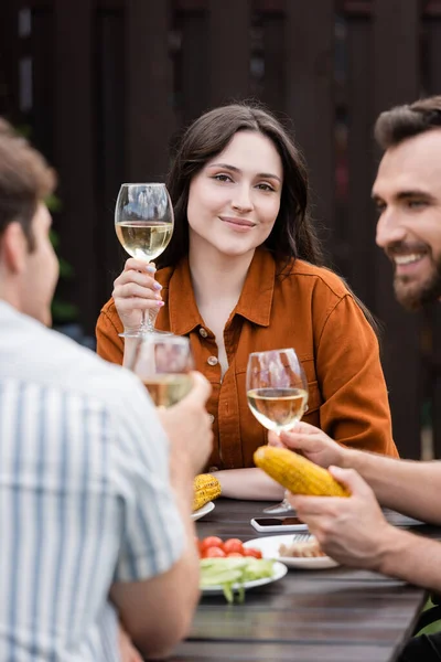 Junge Frau hält Glas Wein in der Hand und blickt beim Picknick im Freien in die Kamera — Stockfoto