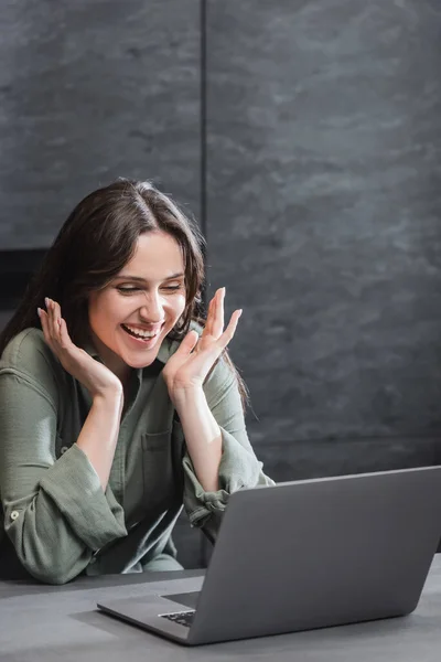 Excited young woman in green shirt looking at laptop while working from home — Stock Photo