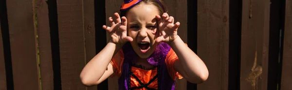 Chica en halloween traje gruñendo y mostrando gesto de miedo, bandera - foto de stock