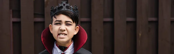 Asiatico ragazzo in vampiro re costume ringhio mentre mostra spaventoso smorfia banner — Foto stock