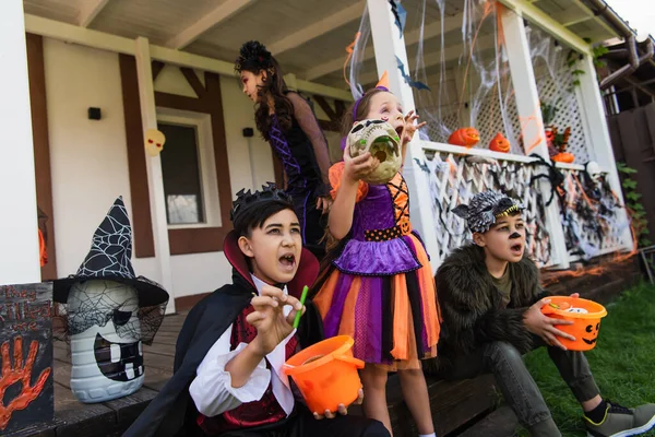 Asiatische Jungen und Mädchen in Halloween-Kostümen grimmig vor geschmücktem Haus — Stockfoto