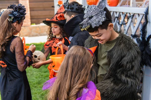 Sourire asiatique garçon en costume parler à ami pendant halloween fête dans arrière-cour — Photo de stock