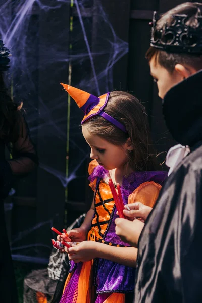 Crianças multiétnicas em trajes festivos segurando doces durante a celebração de Halloween — Fotografia de Stock