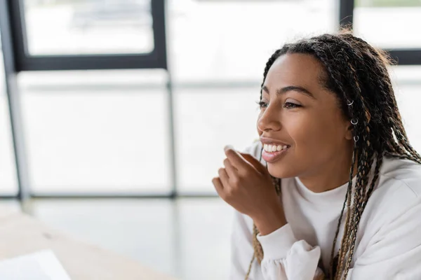 Sonriente mujer de negocios afroamericana mirando hacia otro lado en el cargo — Stock Photo