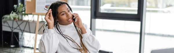 Donna d'affari afroamericana che parla al cellulare in ufficio, striscione — Foto stock