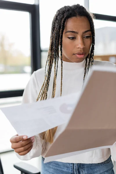 Африканская американская бизнесвумен держит размытую бумажную папку в офисе — стоковое фото