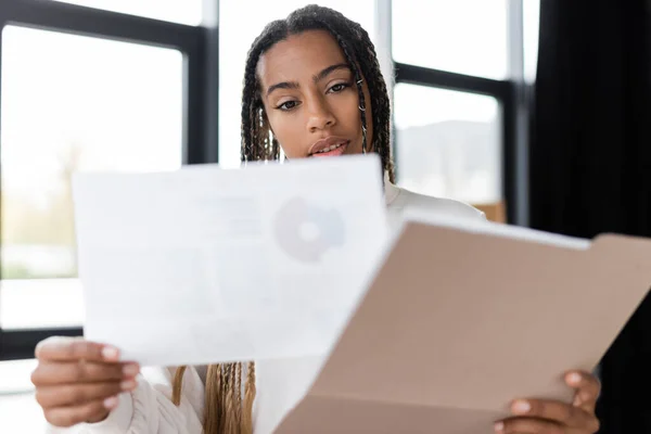 Femme d'affaires afro-américaine tenant document et dossier papier au bureau — Photo de stock