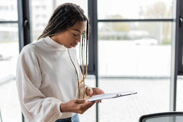 Empresaria afroamericana sosteniendo portapapeles en el cargo — Stock Photo