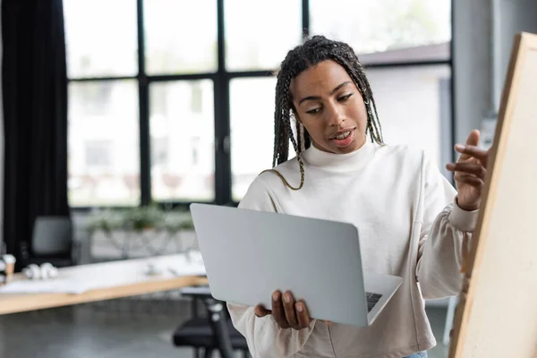 African american businesswoman having video call on laptop near blurred board in office — Stock Photo