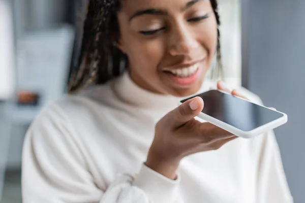 Blurred african american businesswoman recording voice message in office — Stock Photo