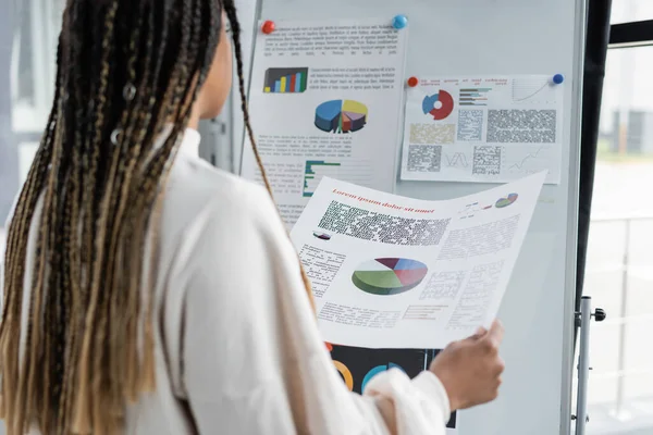Empresaria afroamericana borrosa sosteniendo papel cerca de flip chair en la oficina — Stock Photo