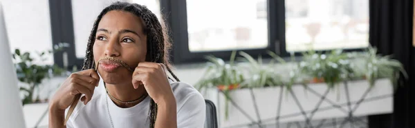 Pensativa mujer de negocios afroamericana tocando el pelo en la oficina, pancarta - foto de stock