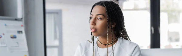 African american businesswoman in t-shirt looking away in office, banner — Stock Photo