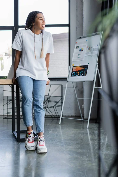 Lächelnde afrikanisch-amerikanische Geschäftsfrau in lässiger Kleidung schaut im Büro weg — Stockfoto