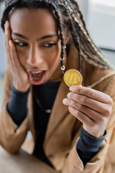 KIEW, UKRAINE - 27. April 2022: Schockierte afrikanisch-amerikanische Geschäftsfrau hält Bitcoin — Stockfoto