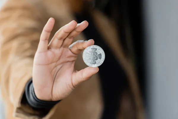 KYIV, UCRANIA - 27 DE ABRIL DE 2022: Vista recortada de la mujer de negocios afroamericana sosteniendo bitcoin de plata - foto de stock