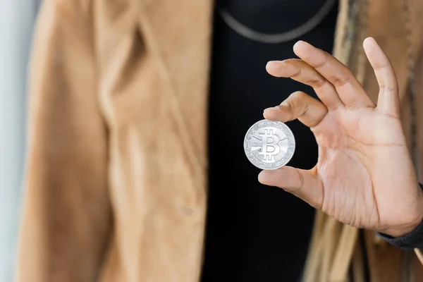 KYIV, UKRAINE - APRIL 27, 2022: Cropped view of blurred african american businesswoman holding silver bitcoin — Stock Photo