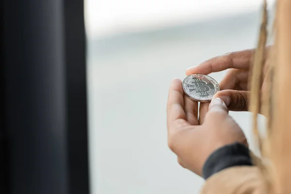 Cropped view of african american businesswoman holding silver bitcoin in office — Stock Photo
