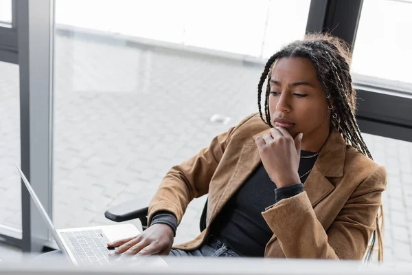 Femme d'affaires afro-américaine ciblée utilisant un ordinateur portable au bureau — Photo de stock