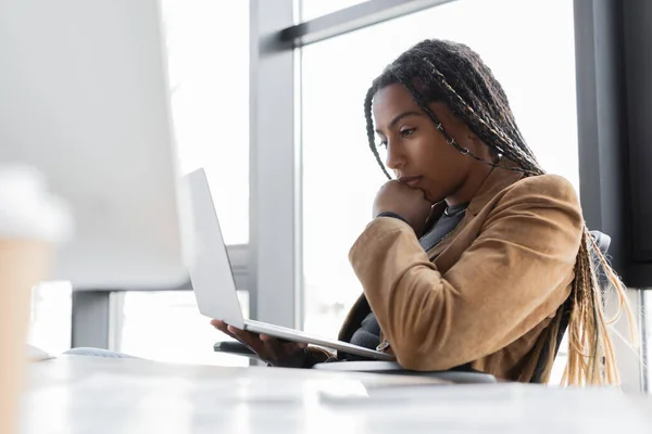 Africano americano empresária em jaqueta segurando laptop no escritório — Fotografia de Stock