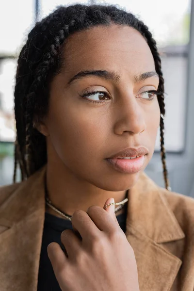 Retrato de mujer de negocios afroamericana tocando collar en la oficina - foto de stock