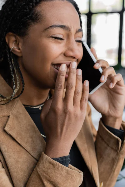 Empresária americana africana alegre em blazer falando no smartphone no escritório — Fotografia de Stock
