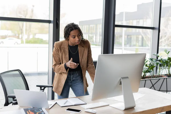 Afroamerikanische Geschäftsfrau zeigt bei Videoanruf auf Computer im Büro mit dem Finger — Stockfoto