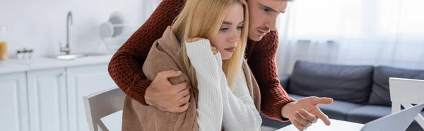Mann im Pullover zeigt auf Laptop neben junger Freundin im Pullover, Transparent — Stockfoto
