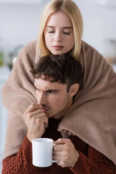 Mulher preocupada segurando cobertor perto namorado estressado com copo — Fotografia de Stock