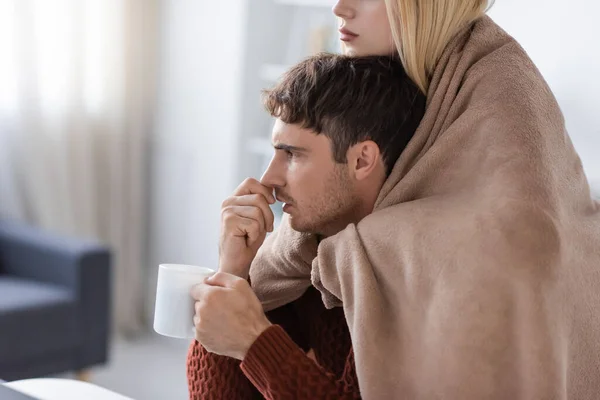 Femme blonde couvrant avec couverture copain tenant tasse de thé — Photo de stock