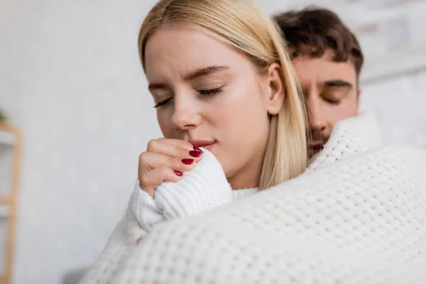 Caring man covering blonde woman in white sweater with blanket at home — Stock Photo