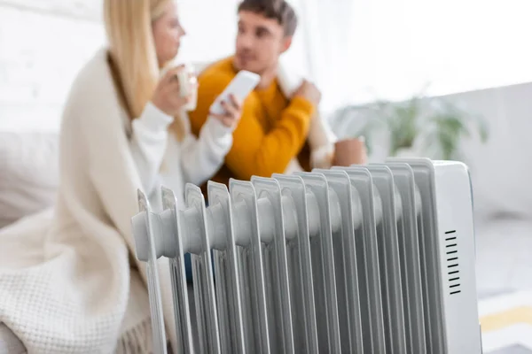 Moderne Heizkörperheizung in der Nähe verschwommenes Paar mit Decke abgedeckt — Stockfoto