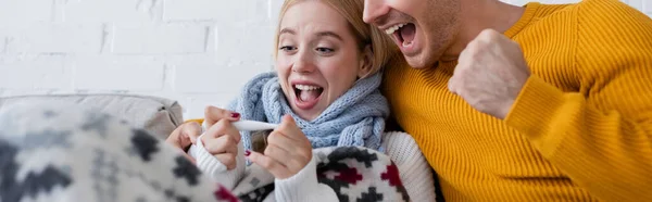 Uomo eccitato e donna bionda malata guardando il termometro digitale, banner — Foto stock