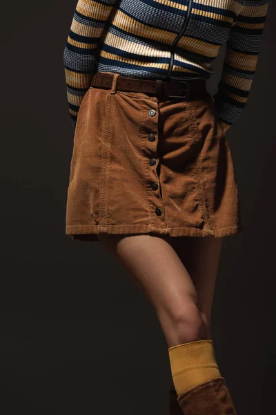 Cropped view of young woman in autumnal skirt standing isolated on black — Stock Photo