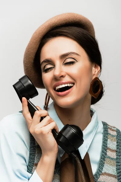 Smiling young woman in beret talking on vintage telephone isolated on grey — Stock Photo
