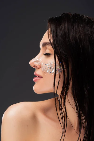 Profil der jungen brünetten Frau mit natürlichem Make-up und funkelndem Glitzern auf den Wangen vereinzelt auf grau — Stockfoto