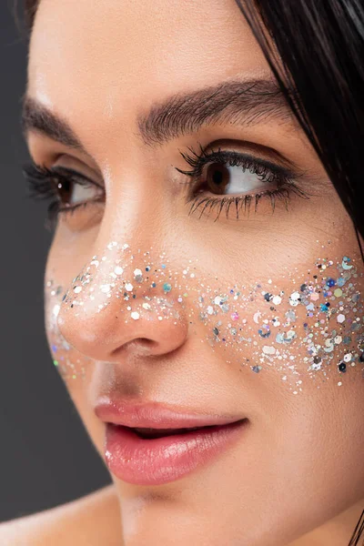 Close up of young brunette woman with shiny glitter on cheeks isolated on grey — Stock Photo