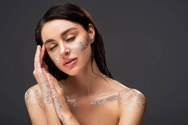 Portrait of sleepy woman with sparkling glitter on cheeks and hands isolated on grey — Stock Photo