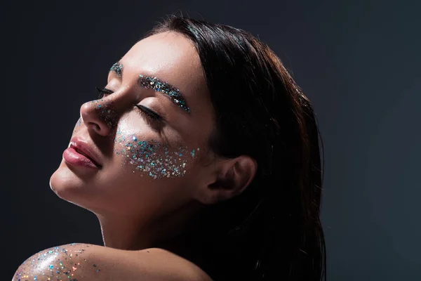 Portrait of young woman with closed eyes and glitter on eyebrows isolated on grey — Stock Photo