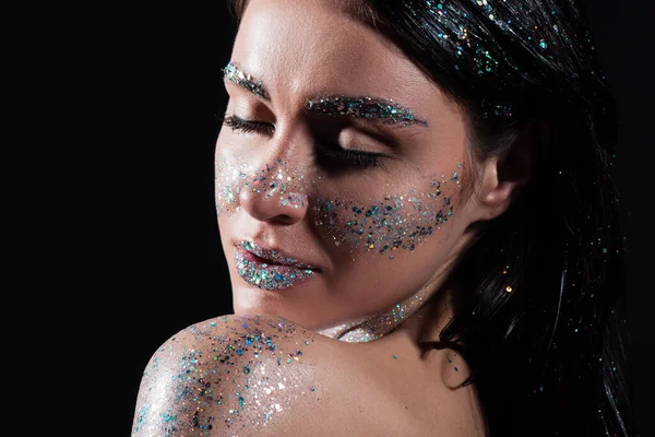 Retrato de mujer joven con los ojos cerrados y chispa brillo en el cuerpo aislado en negro - foto de stock