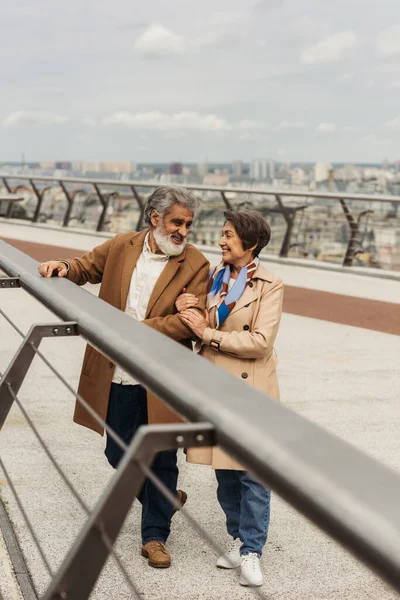 Feliz mulher sênior abraçando marido barbudo perto ponte guarda ferroviário — Fotografia de Stock