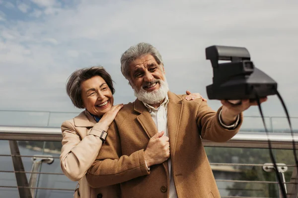 Happy senior man taking selfie with cheerful wife on vintage camera — Stock Photo