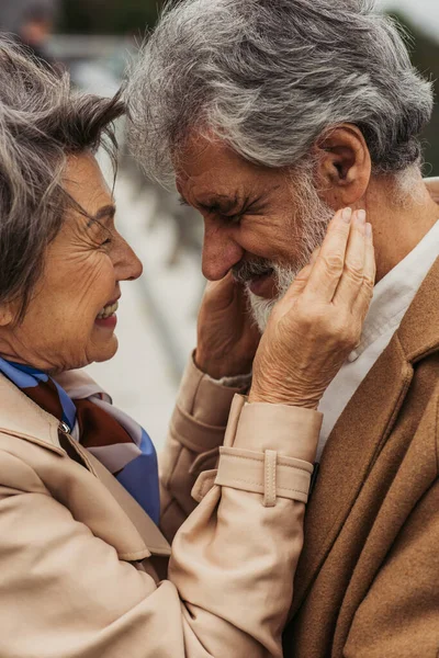 Portrait de femme âgée gaie embrassant mari barbu en manteau beige — Stock Photo