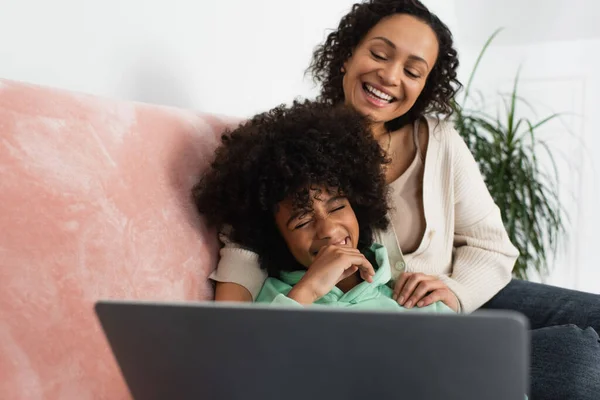 Счастливая африканская мать и дочь смотрят комедийный фильм на ноутбуке — стоковое фото