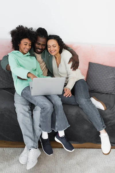Високий кут зору радісної афроамериканської сім'ї дивитися комедійний фільм на ноутбуці, сидячи на дивані — стокове фото