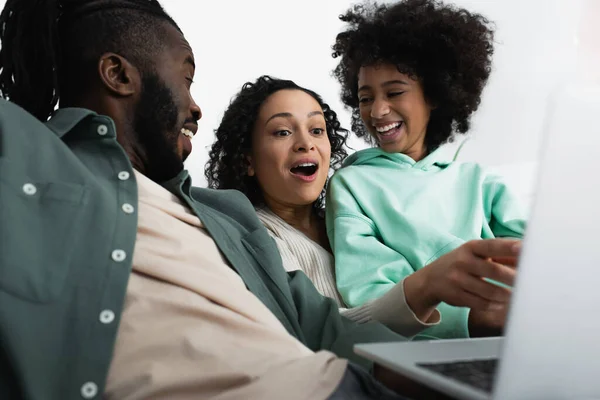Erstaunt afrikanisch-amerikanische Frau schaut auf Laptop in der Nähe glücklicher Tochter und Ehemann — Stockfoto