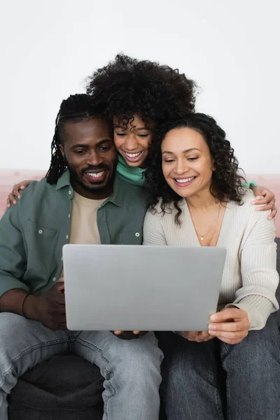 Feliz africano americano padres y preadolescente chica viendo película en portátil en sala de estar - foto de stock