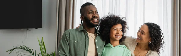 Happy african american parents and cheerful preteen girl smiling at home, banner — Stock Photo