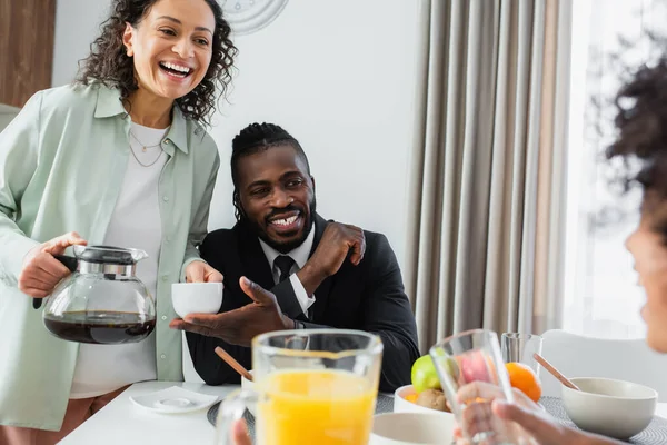 Feliz afro-americanos pais olhando encaracolado preteen filha durante o café da manhã — Fotografia de Stock
